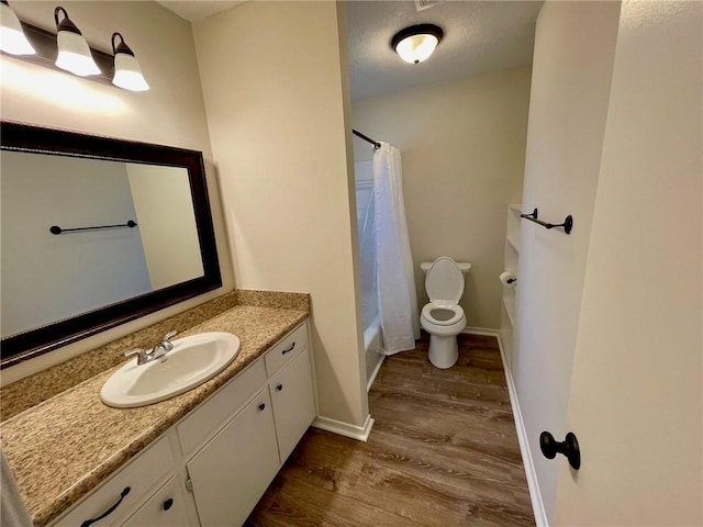 full bathroom featuring toilet, wood-type flooring, shower / tub combo with curtain, vanity, and a textured ceiling