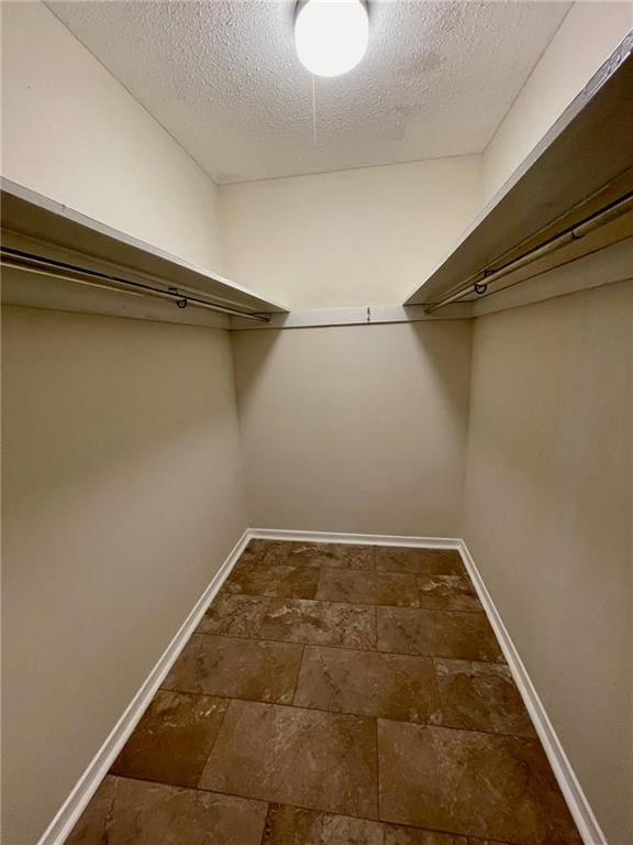 spacious closet featuring stone tile floors