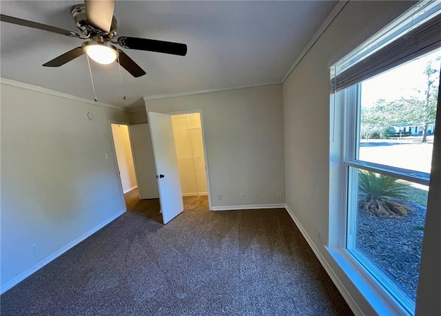 carpeted empty room with a ceiling fan, baseboards, and ornamental molding