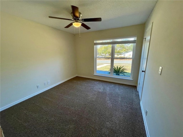 unfurnished room featuring baseboards, a textured ceiling, ceiling fan, and dark carpet