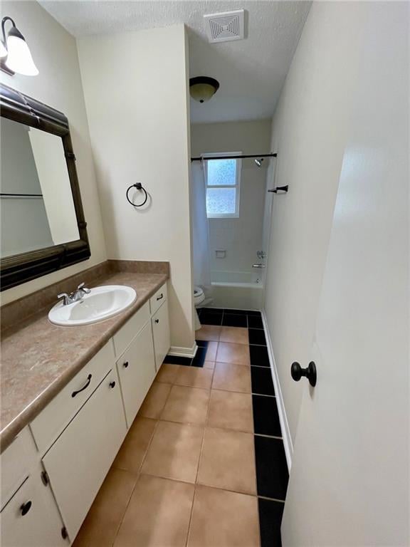 full bathroom with tile patterned floors, toilet, shower / bath combo with shower curtain, vanity, and a textured ceiling