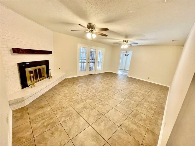 unfurnished living room with ceiling fan, a brick fireplace, a textured ceiling, french doors, and light tile patterned floors