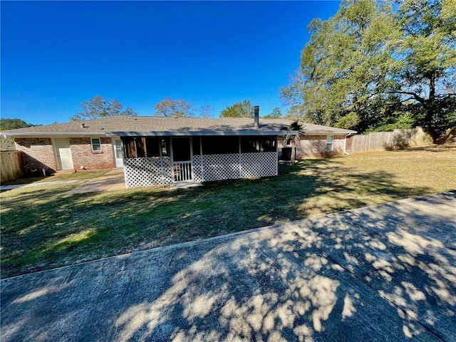 back of property featuring fence, a yard, a sunroom, and brick siding