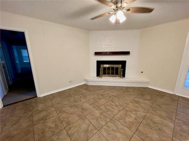 unfurnished living room with a brick fireplace, a ceiling fan, a textured ceiling, and tile patterned flooring