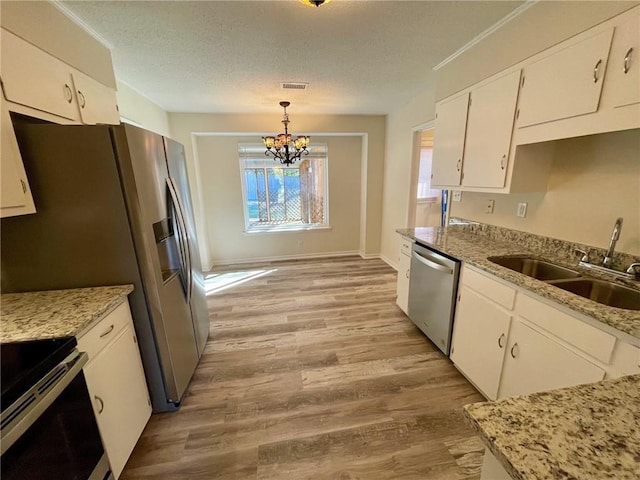 kitchen featuring white cabinetry, light hardwood / wood-style flooring, sink, pendant lighting, and stainless steel appliances