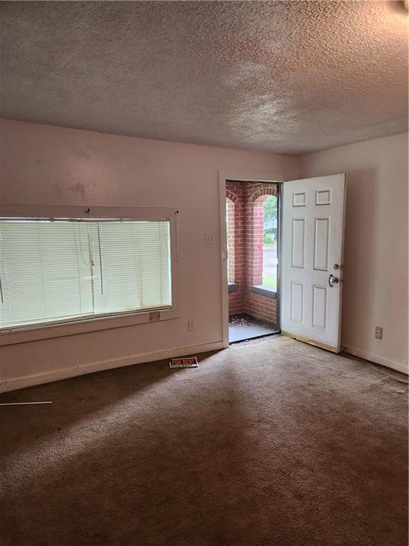 spare room featuring a textured ceiling and carpet floors