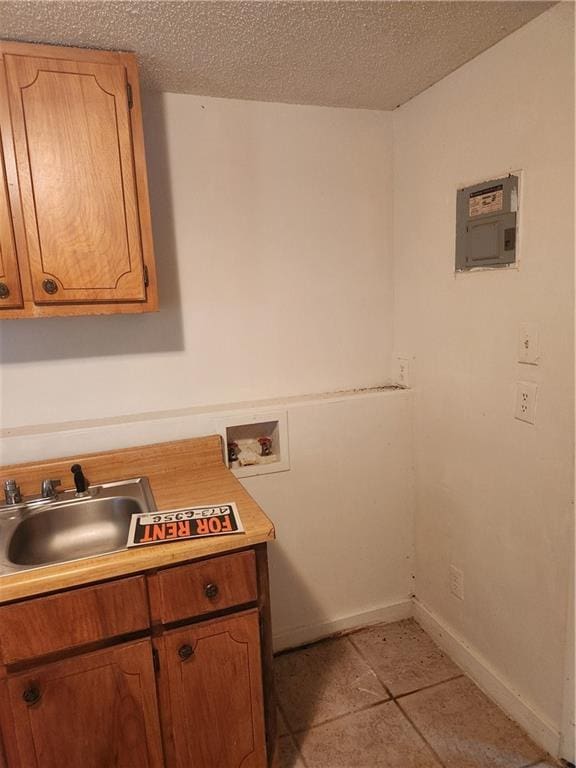 laundry room with cabinets, light tile patterned floors, washer hookup, a textured ceiling, and sink