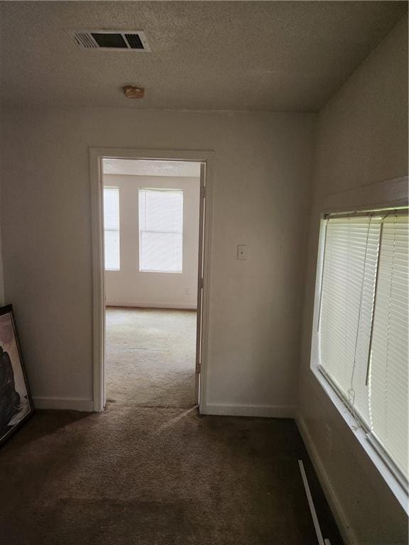 hall featuring carpet flooring and a textured ceiling