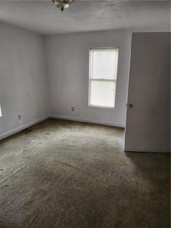 spare room featuring a textured ceiling and dark colored carpet