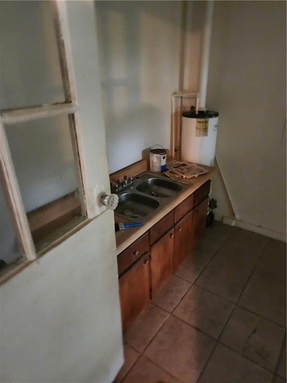 kitchen featuring sink, electric water heater, and light tile patterned flooring