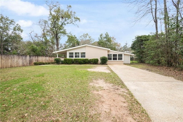 view of front of property with concrete driveway, fence, and a front lawn