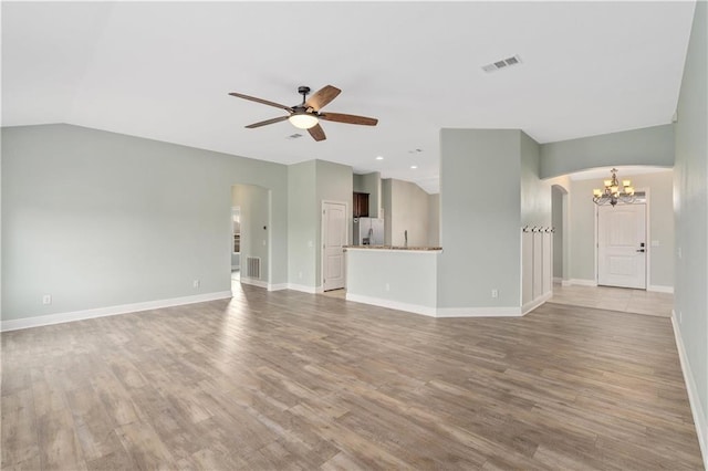 unfurnished living room featuring vaulted ceiling, ceiling fan with notable chandelier, and light hardwood / wood-style flooring