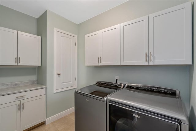 laundry room with cabinets, washing machine and dryer, and light tile patterned floors