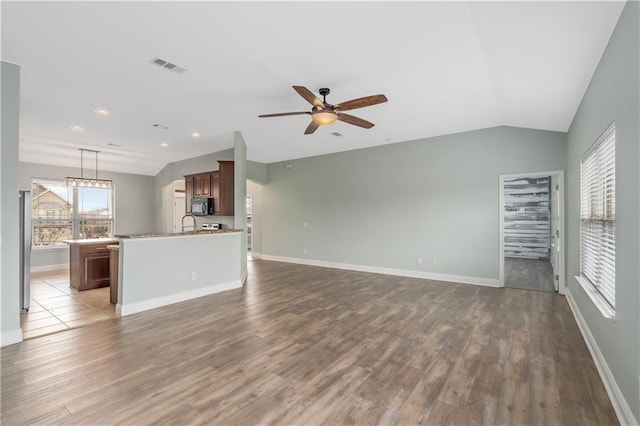 unfurnished living room featuring ceiling fan, vaulted ceiling, and hardwood / wood-style floors