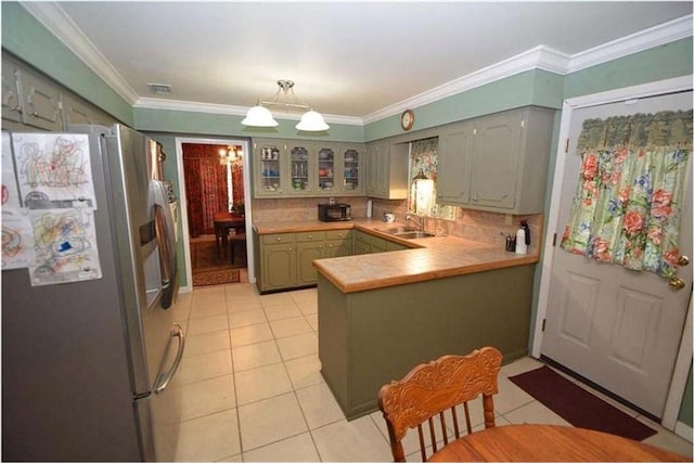 kitchen with kitchen peninsula, ornamental molding, stainless steel fridge, sink, and light tile floors