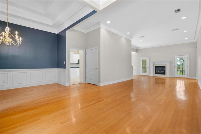 unfurnished living room with a fireplace, crown molding, a notable chandelier, and light hardwood / wood-style floors