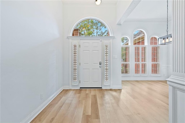 entrance foyer featuring a notable chandelier, light wood-type flooring, and ornamental molding