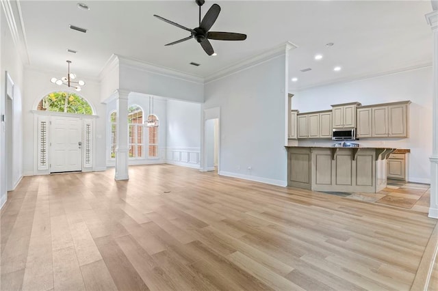 unfurnished living room featuring ceiling fan with notable chandelier, ornamental molding, light hardwood / wood-style flooring, and ornate columns