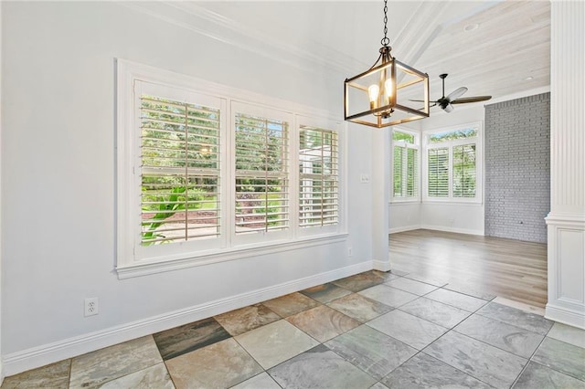 unfurnished dining area with a healthy amount of sunlight, ceiling fan with notable chandelier, and ornamental molding