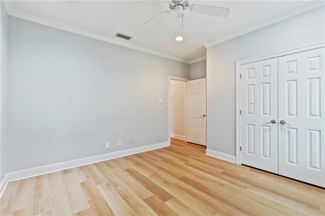 unfurnished bedroom featuring ceiling fan, light wood-type flooring, crown molding, and a closet