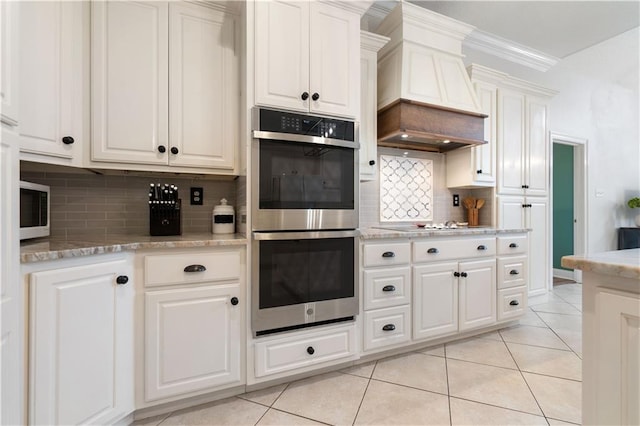 kitchen featuring backsplash, crown molding, custom range hood, double oven, and white cabinetry