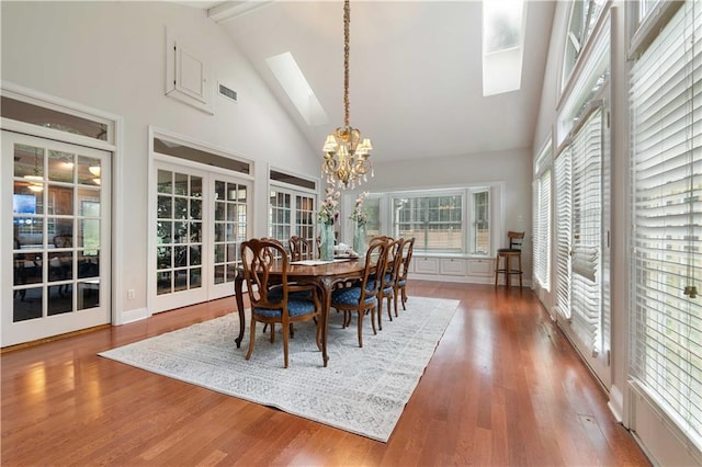 dining room with a skylight, beamed ceiling, high vaulted ceiling, a notable chandelier, and wood-type flooring