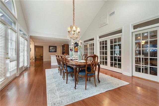 dining space featuring french doors, high vaulted ceiling, dark hardwood / wood-style floors, and a notable chandelier