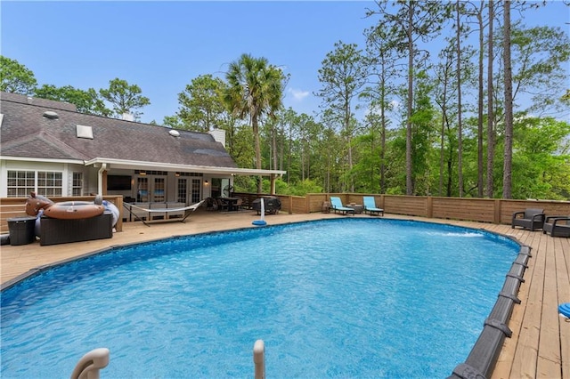 view of pool with french doors and a wooden deck