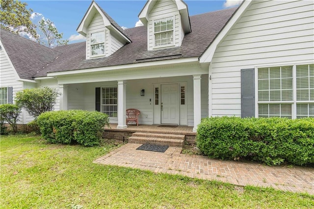 doorway to property featuring covered porch and a yard