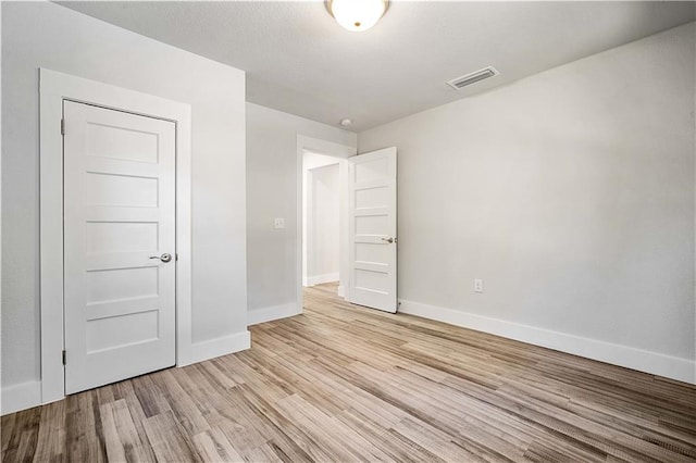 unfurnished bedroom featuring baseboards, visible vents, and light wood-style floors