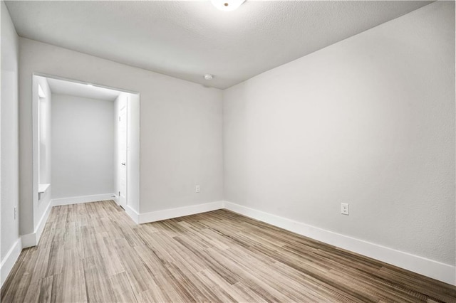 unfurnished room with light wood-type flooring and baseboards