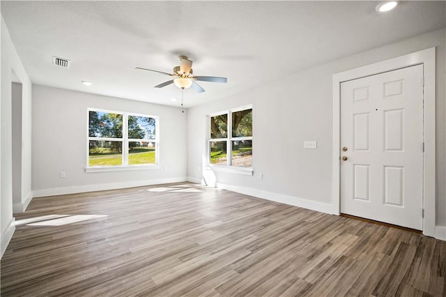 interior space featuring dark wood-type flooring, a ceiling fan, visible vents, and baseboards