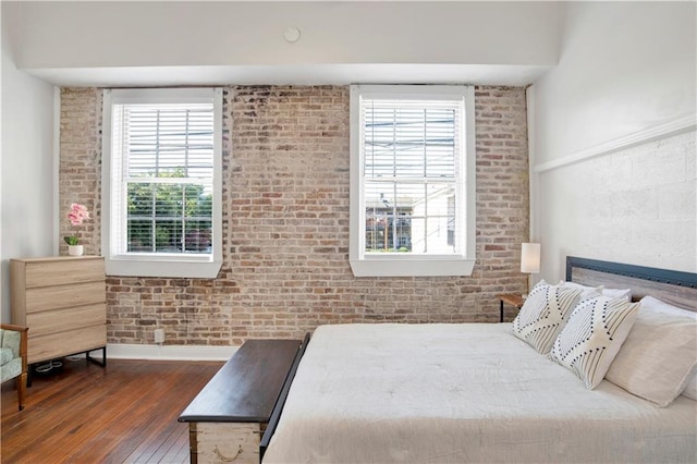 bedroom with brick wall, dark wood-type flooring, and multiple windows