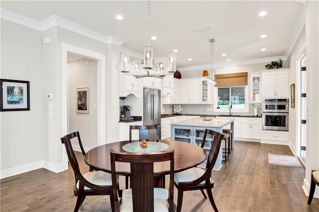 dining space featuring ornamental molding, sink, dark hardwood / wood-style floors, and a chandelier