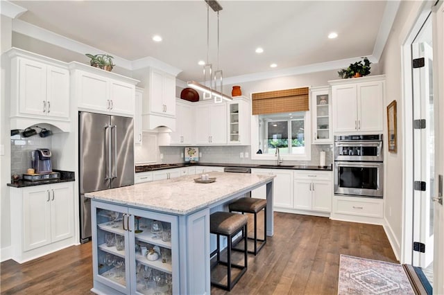 kitchen with tasteful backsplash, a kitchen island, hanging light fixtures, stainless steel appliances, and dark hardwood / wood-style floors