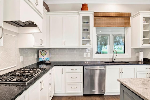 kitchen featuring tasteful backsplash, appliances with stainless steel finishes, sink, white cabinetry, and dark stone countertops