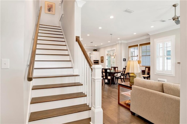 stairway featuring crown molding, wood-type flooring, and ceiling fan