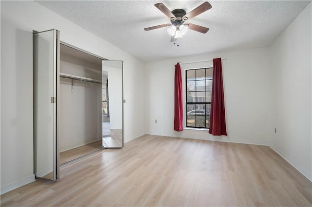 unfurnished bedroom with a closet, light wood-style floors, a ceiling fan, and a textured ceiling