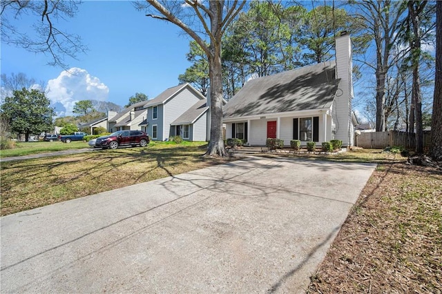 view of front of home with a front yard, a porch, a chimney, and fence