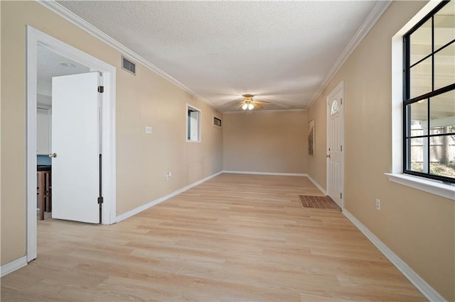 empty room featuring crown molding, light wood-style flooring, visible vents, and a textured ceiling