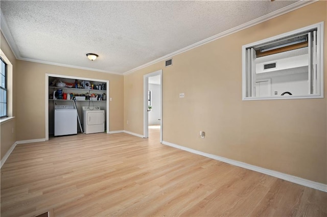 spare room with light wood-style floors, visible vents, independent washer and dryer, and a textured ceiling