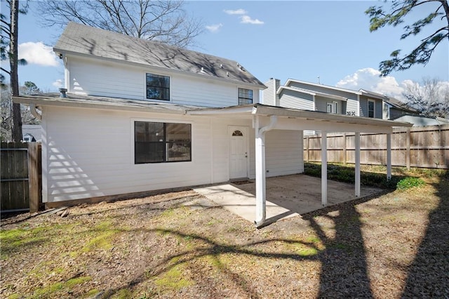 rear view of property featuring a patio, dirt driveway, and fence