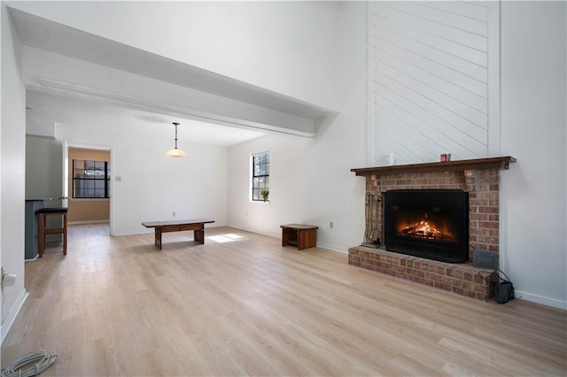 unfurnished living room featuring a brick fireplace, light wood-type flooring, and baseboards