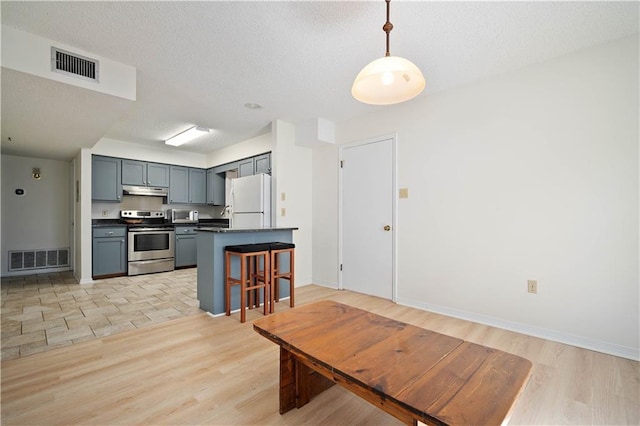 kitchen with dark countertops, visible vents, appliances with stainless steel finishes, and under cabinet range hood