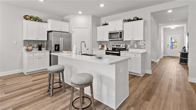 7320 Hawkins Mnr S, Mobile, AL 36695 - kitchen featuring stainless steel appliances, decorative backsplash, light countertops, a kitchen bar, and a kitchen island with sink