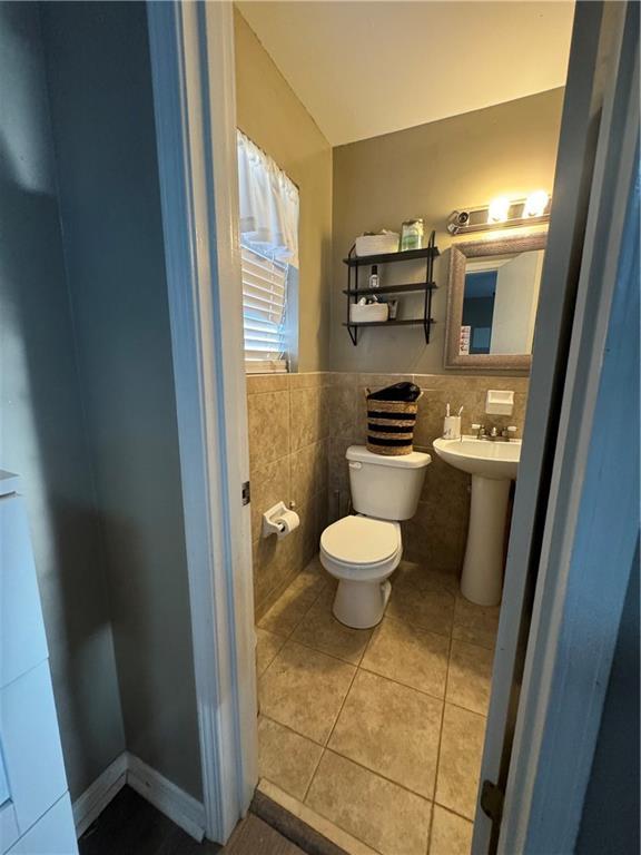 bathroom with tile patterned floors, sink, toilet, and tile walls