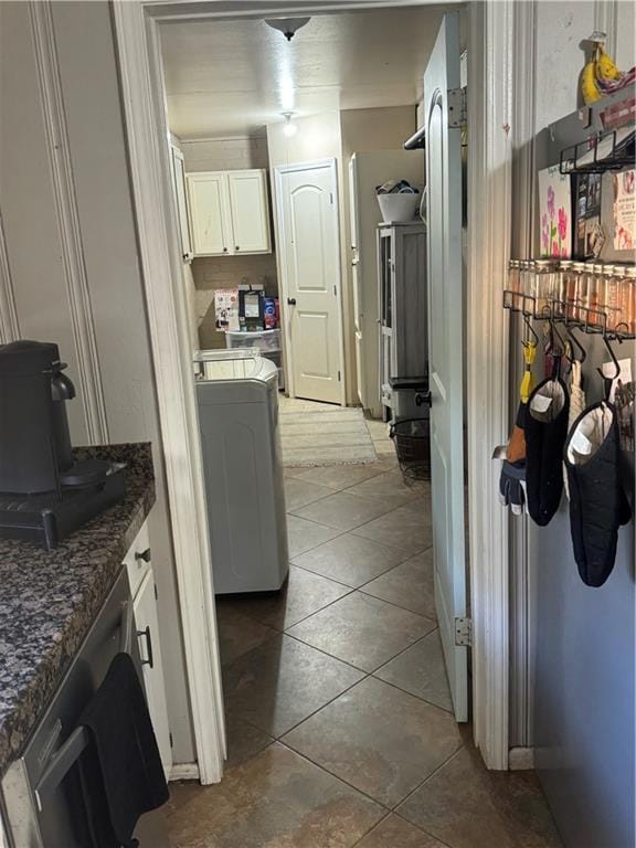 kitchen featuring tile patterned floors, dark stone countertops, white cabinets, and washer / dryer