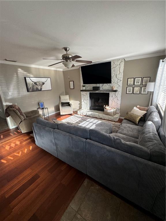 living room with a fireplace, hardwood / wood-style floors, ceiling fan, and crown molding