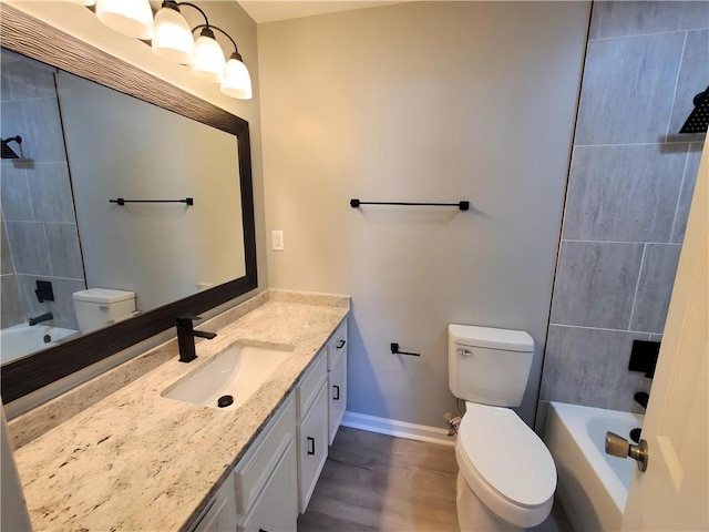 full bathroom featuring tiled shower / bath, vanity, wood-type flooring, and toilet