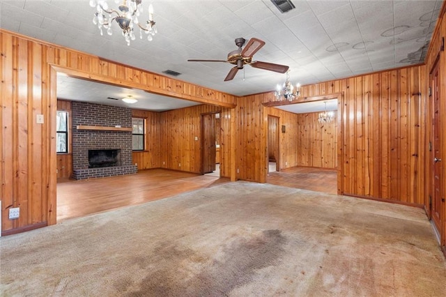 unfurnished living room with light carpet, a brick fireplace, and ceiling fan with notable chandelier